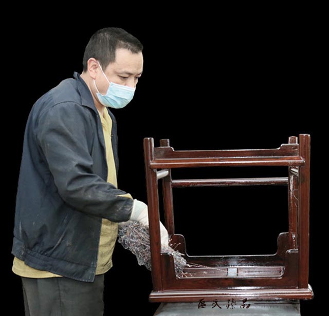 區(qū)氏臻品工匠正在對一件家具仔細上生漆。這道工序，讓紅木家具一下子有了溫潤的質感